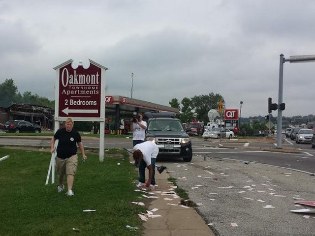 Volunteers clean after riots in Ferguson Sunday night as a news crew looks on.