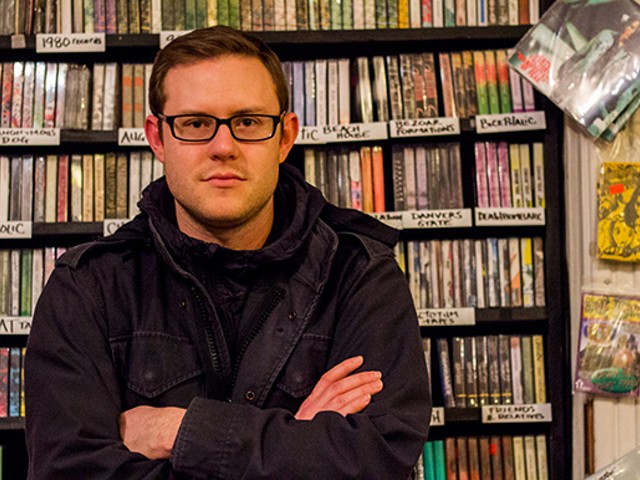 Nathan Cook stands among the wall of tapes at Apop Records.