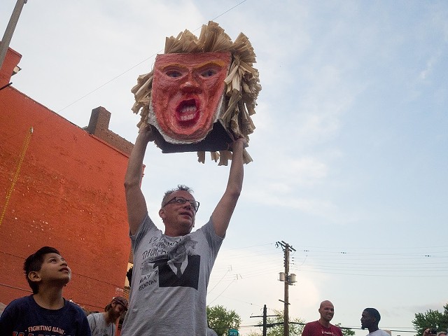 Francis "Rich" Rodriguez, owner of Yaquis on Cherokee, holds El Trumpo's severed head aloft.