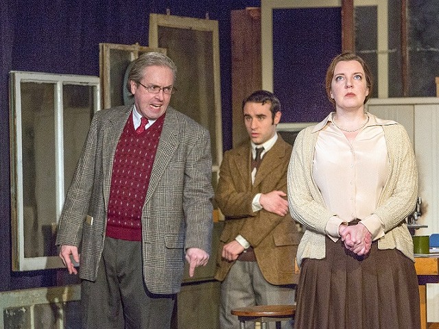 Maurice Wilkins (Ben Ritchie, left) upbraids an unrepentant Rosalind Franklin (Nicole Angeli, right) while a stunned Ray Gosling (Ryan Lawson-Maeske, in the back) stands clear.