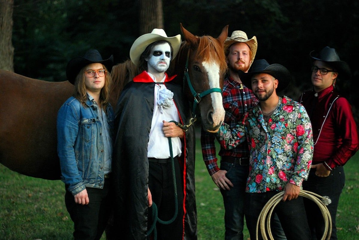 Dracla, alongside the bandmates he barely tolerates, and a horse.