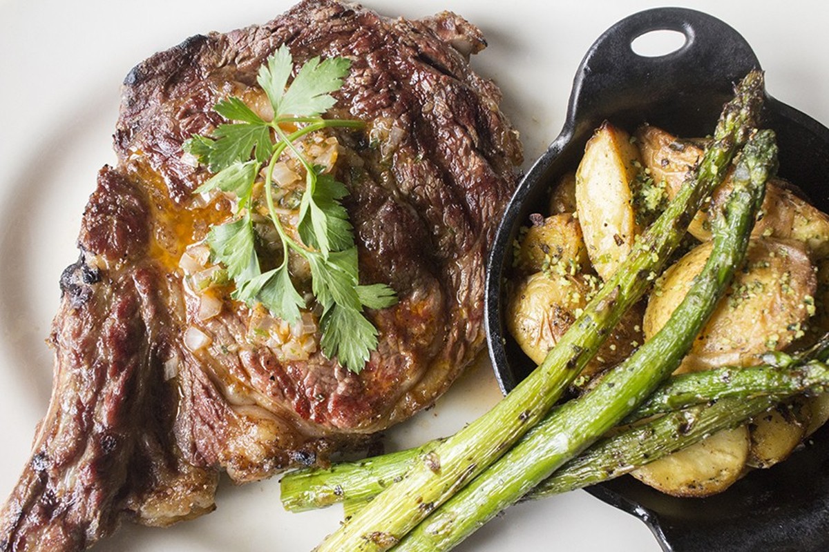 Weber Grill Restaurant’s bone-in ribeye steak is served  with asparagus and potatoes.
