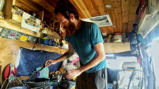John Serbell fixes a meal in the van he and Jayme Serbell transformed into a home.