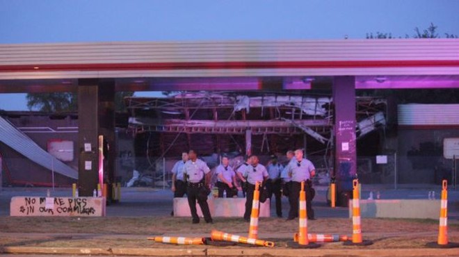 Police guard the burnt-out, graffitied QuikTrip in Ferguson.