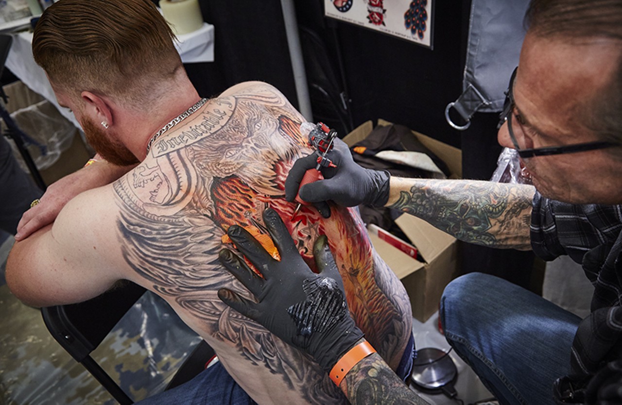 Rob Johnson of All Star Tattoo works on Eric Thomas' back tat.