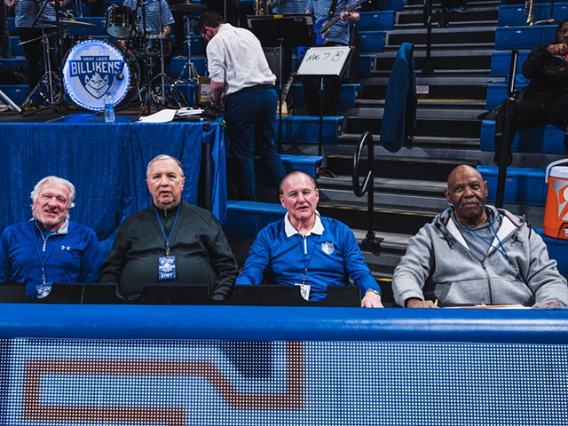 (From left) Mike Van Hecke, Mike Owens, Ken Mraz and Ron Golden sit at a blue table in front of bleachers and a band.