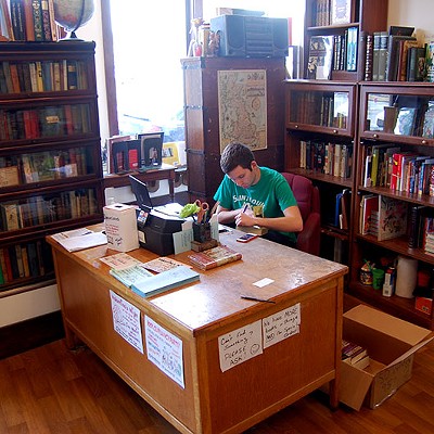 Employee Mark Gould works at the desk. Both employees and regulars may remember the original location in a historic Victorian house. That location closed in 2013, and after some fundraising, the store has been in the current location ever since.