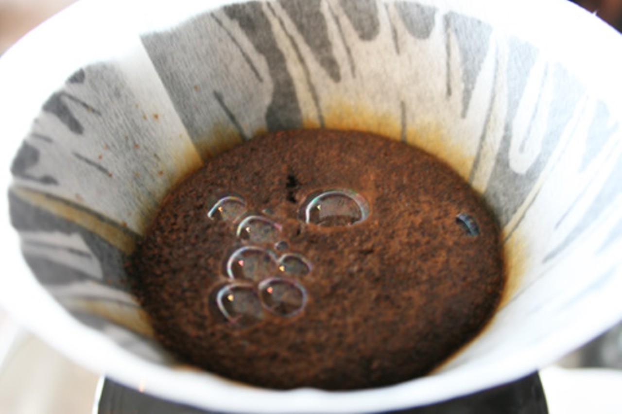 A flash-brewed cup of coffee produces bubbles as it filters.