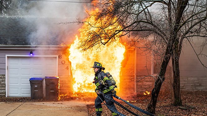 A firefighter with the Florissant Valley Fire Protection District stretches a water hose to extinguish a house fire on Friday, Jan. 26, 2024, in Florissant.