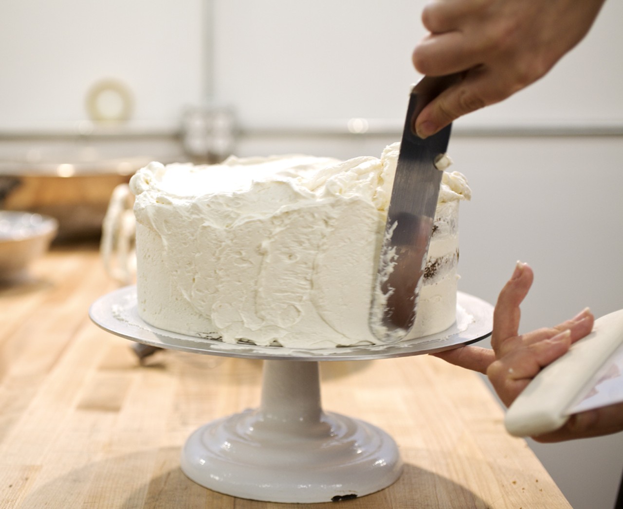Bittersweet owner Leanna Russo applies icing to a Vanilla Bean Buttermilk cake in the kitchen at Bittersweet.
