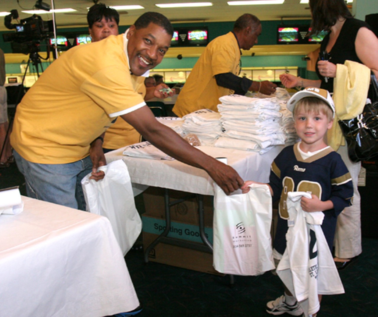 Rams fans of all ages went to Tropicana Lanes to see Rams players and bowl. Shown getting some goodies from Dwane Gibson is Kirk Briden, 5.