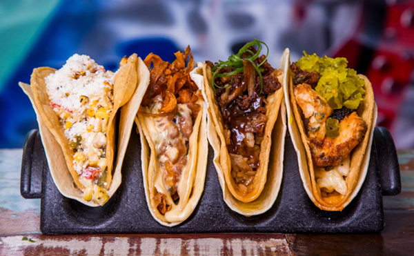 A row of four tacos sit on a table.