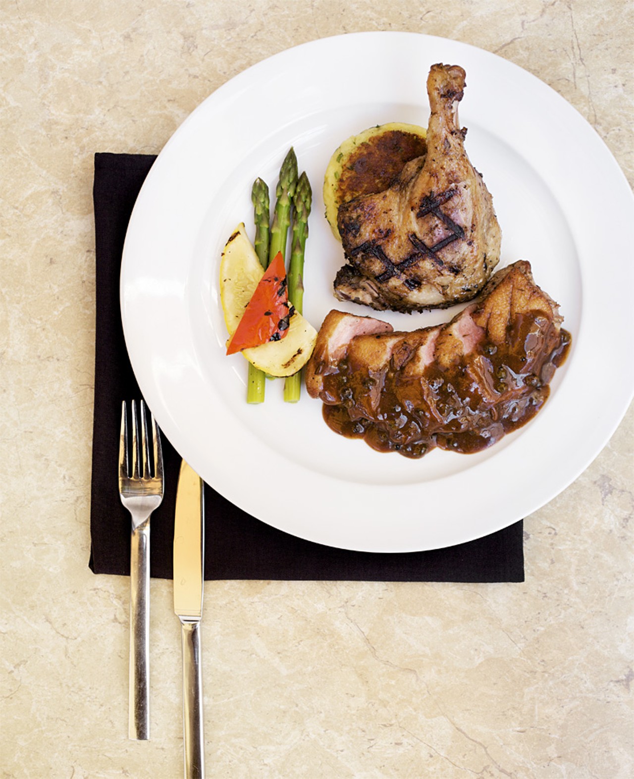 The Grilled Duck Breast with Confit Leg is served with candied date peppercorn pan gravy, Maytag bleu cheese potato cake and fresh vegetables.