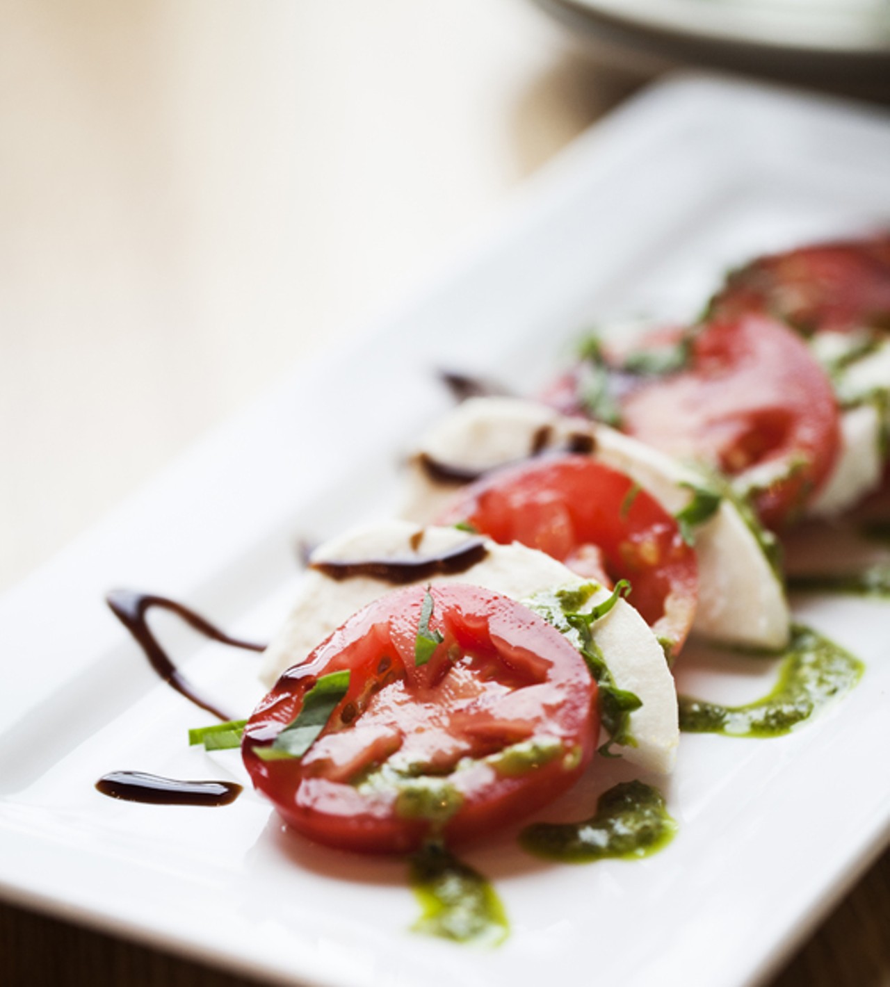 Fresh Mozzarella is served with tomato, basil pesto and a balsamic reduction.