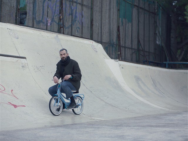 Aris attempts to recapture his memory by completing a series of human milestones, including riding a child's tiny two-speed at a skate park, and documenting them with a Polaroid camera.