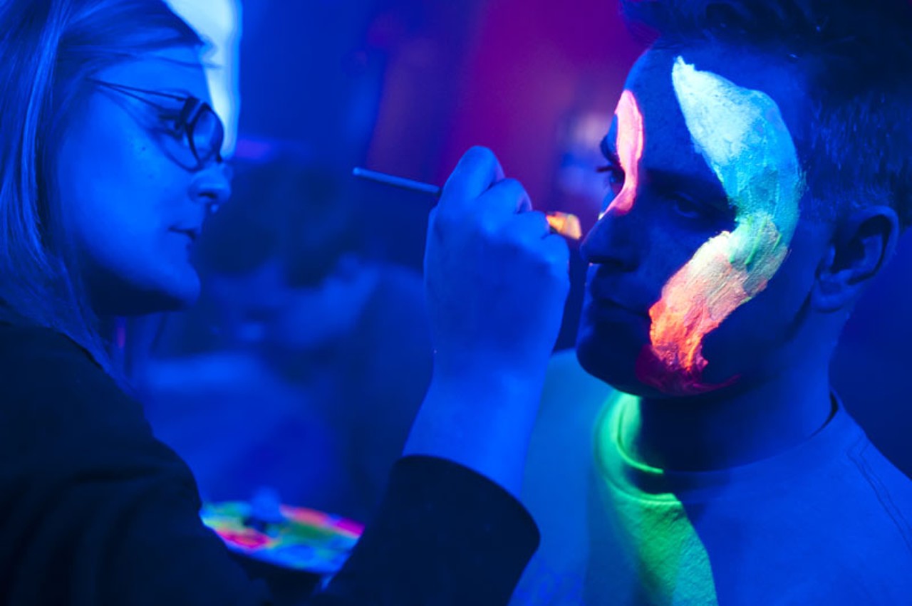 An attendee at the Electro Snow Glow helps out another party-goer with some paint at the Crack Fox on Saturday night.