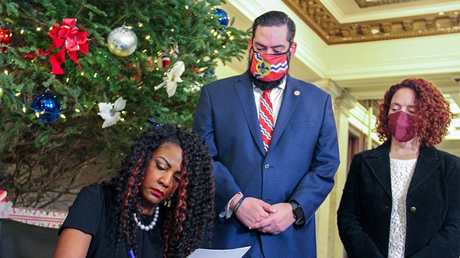 Alderpersons Bret Narayan and Annie Rice look on as St. Louis Mayor Tishaura signs a marijuana decriminalization bill into law on December 13.