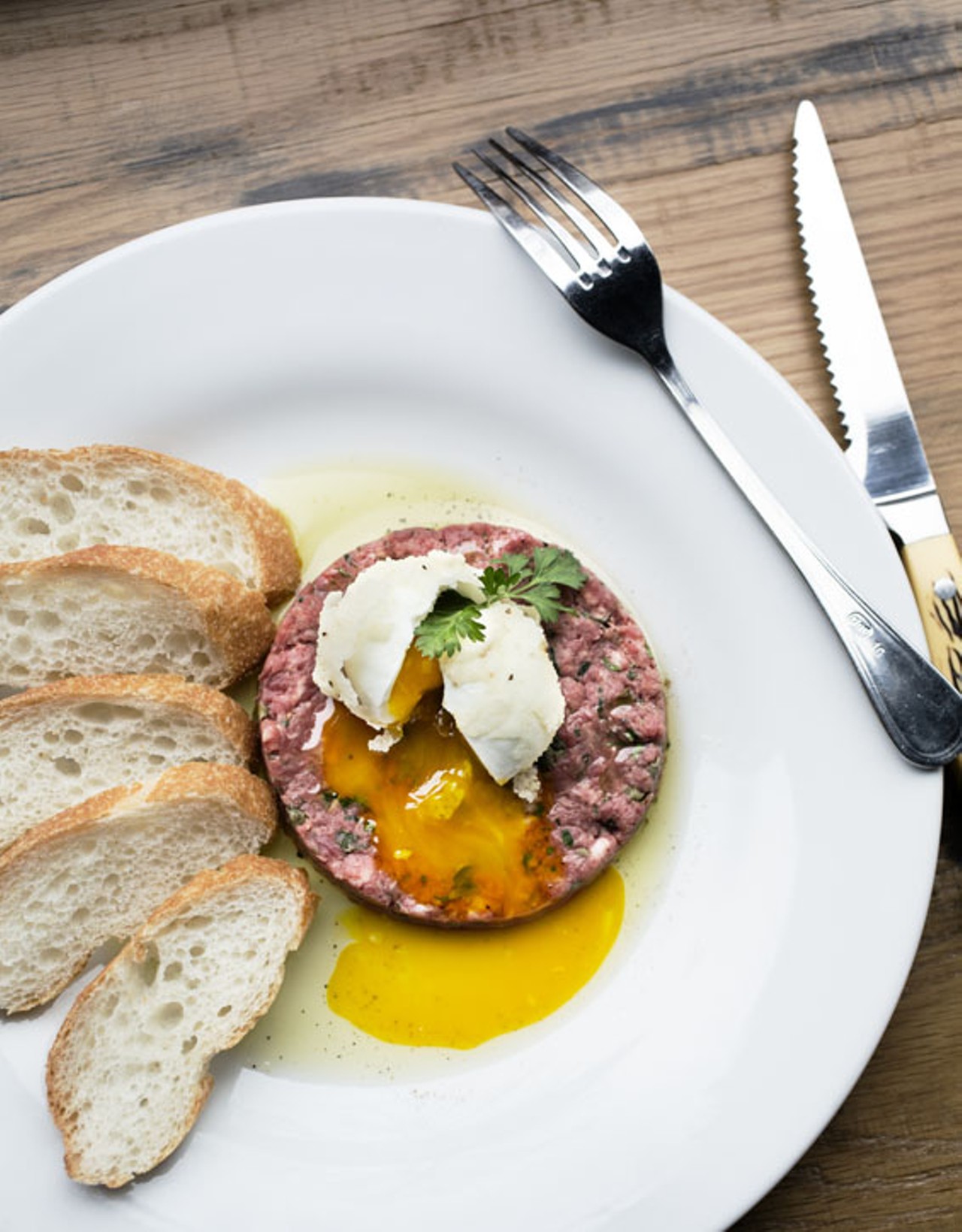 The steak tartare is hand-cut beef tenderloin, capers and cornichons topped with a golden egg and served with a baguette.