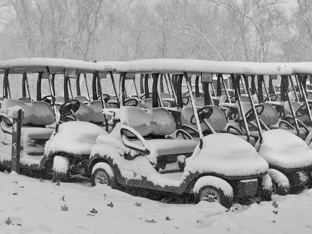Golf carts covered in snow.
