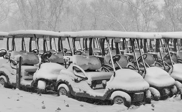Golf carts covered in snow.