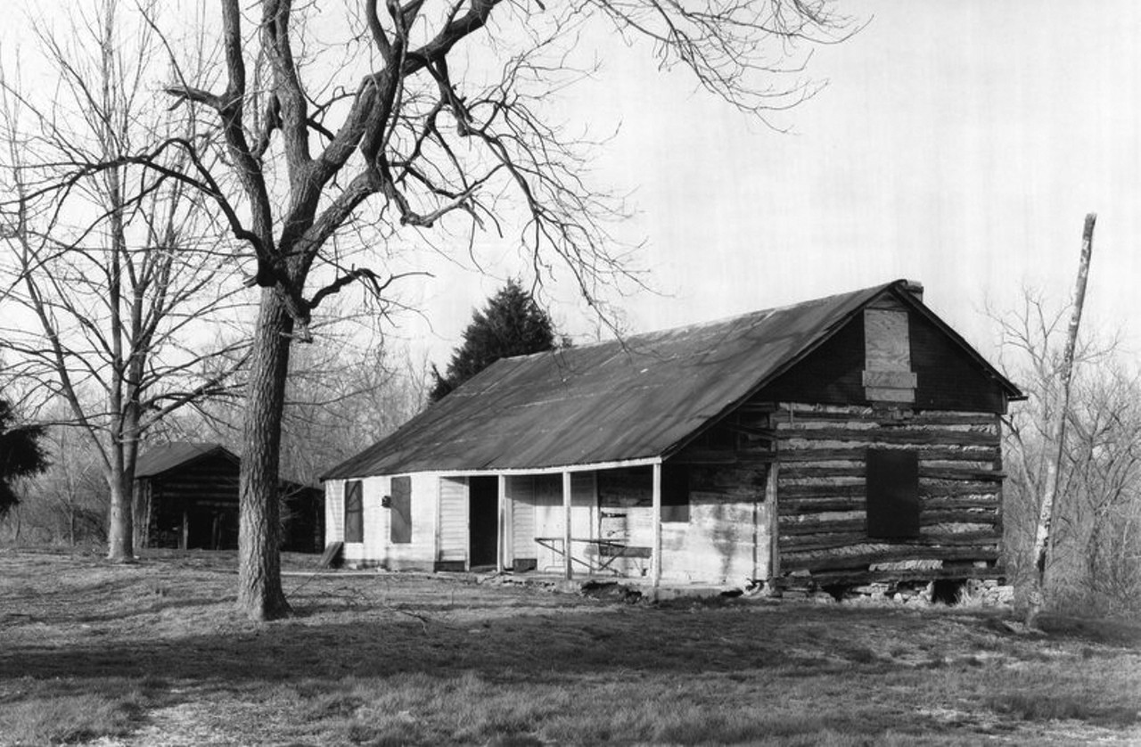 This Used to Be: Mertz Cabin
Now It's: Maryville University land
Location: Town & Country, MO
Conway Road is one of the coolest roads in St. Louis, and Harris digs into its history. "In 1961, the Religious of the Sacred Heart purchased the acreage between Conway Road and Interstate 40 for the new West County Campus of Maryville College. The college told the southern border it ifs property facing highway 40, including a log farmhouse built by nineteenth-century settlers Ludwig and Katherine Mertz, for development as the [Maryville Center] corporate park. The log home stood on the site while the office buildings of the corporate park rose above it."
"The Ludwig and Katerine Mertz log house in its original setting on the Maryville campus. The original chinking between the logs is still visible on the end wall." Image courtesy of the St. Louis County Parks Department.