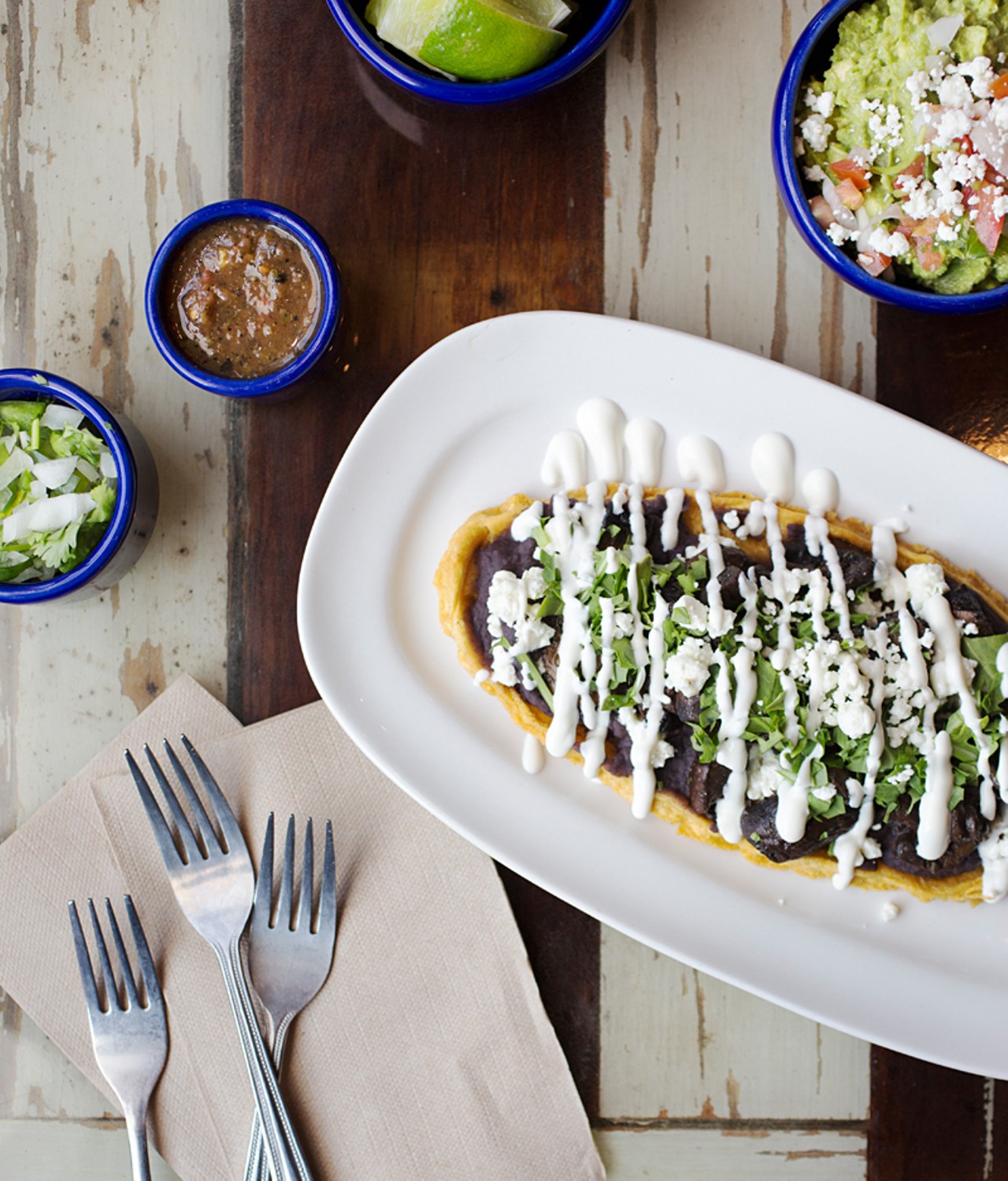The "Wild Mushroom Huarache" is refried black beans, roasted mushrooms, uitlacoche, goat cheese, arugula and Mexican crema in a crisped corn masa boat. Shown here with the fresh-made guacamole, topped with pico de gallo and queso fresco.