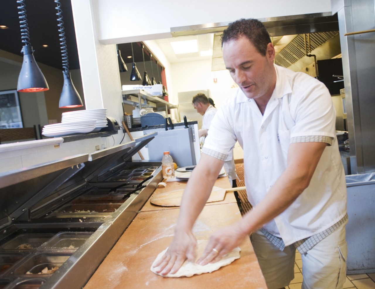 John Racanelli, owner of the Racanelli Empire, says one of the secrets to his pizza is working it on the board. The more you work it, the more air you get out of the dough, creating fewer air bubbles when cooking.