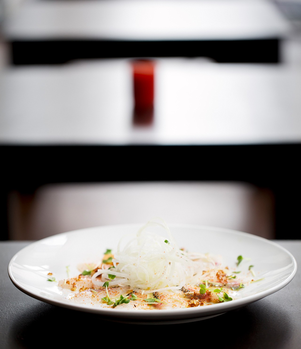 White fish carpaccio is dressed with olive oil, yuzu dressing, five-spice seasoning and garlic chips.