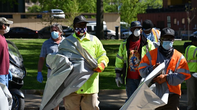 City workers with trash bags head into one of the tent cities on Friday.