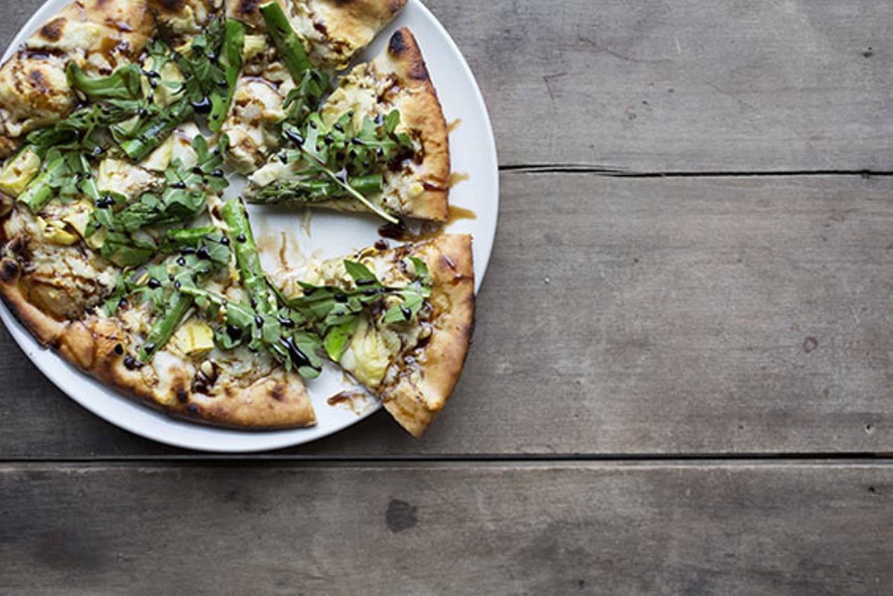Asparagus pizza with extra virgin olive oil, asparagus, artichokes, pine nuts, fontina, balsamic reduction, fresh arugula.