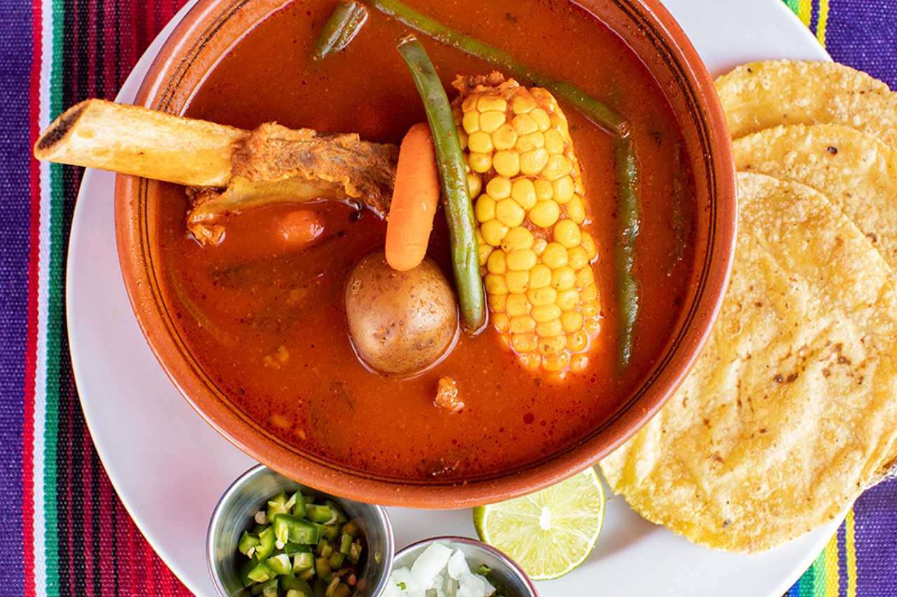 Caldo de res, a soup made with beef bones, potatoes, corn, baby carrots and green beans, served with onions, tortillas and lime.