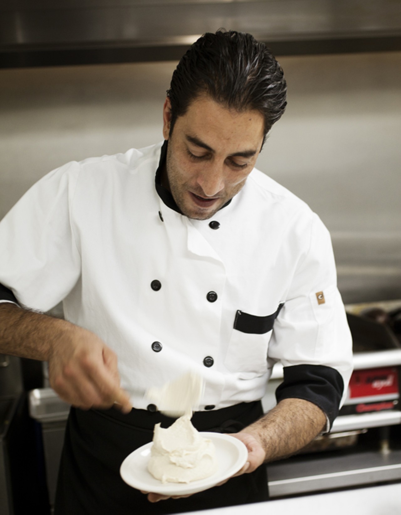 Chef Wasam Hamed in the kitchen at Layla, plating the hummus.