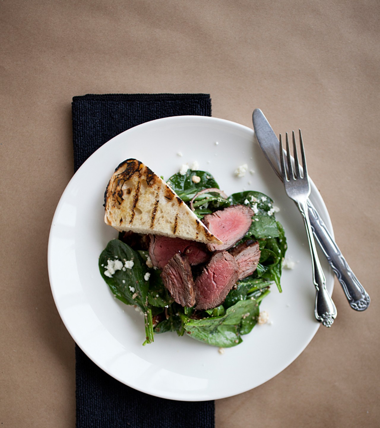 Steak and spinach salad with feta, red onion, roasted tomatoes, grilled beef tenderloin, and balsamic dressing.