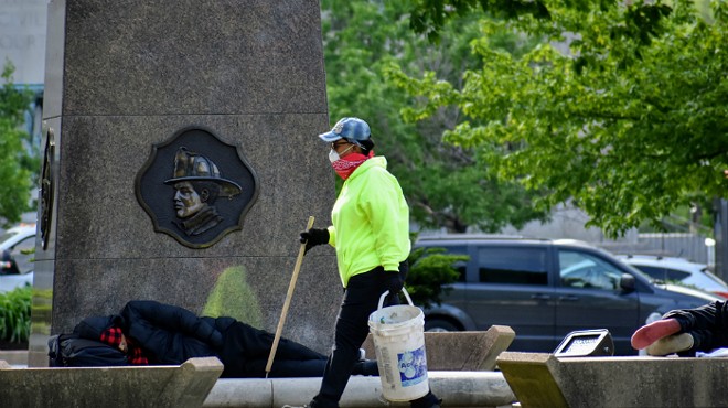 A worker picks up trash after the city removed two tent camps from downtown parks.