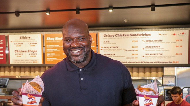 Shaquille O'Neal stands in front of Big Chicken holding two orders.