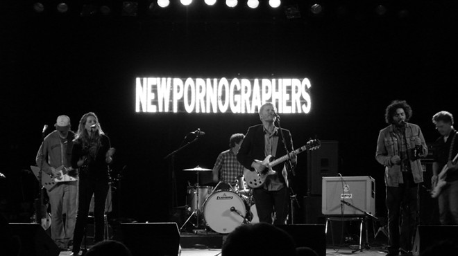 A band plays in front of a sigh that reads "New Pornographers."