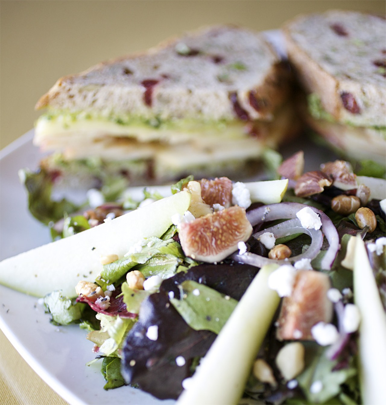 The Harvest Salad is prepared with fresh organic herbed spring mix, organic pears and figs, red onion, gorgonzola, dried fruit, seed and nut mixture tossed in house made cranberry vinaigrette. Shown here with the Orchard Melt sandwich.