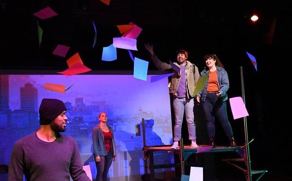 A man dressed in jeans, a khaki jacket, sweater and knit cap tosses colorful paper into the air as three casually dressed people look on from various places on the stage in a scene from Adam Gwon’s ‘Ordinary Days’ at Tesseract Theatre Company.