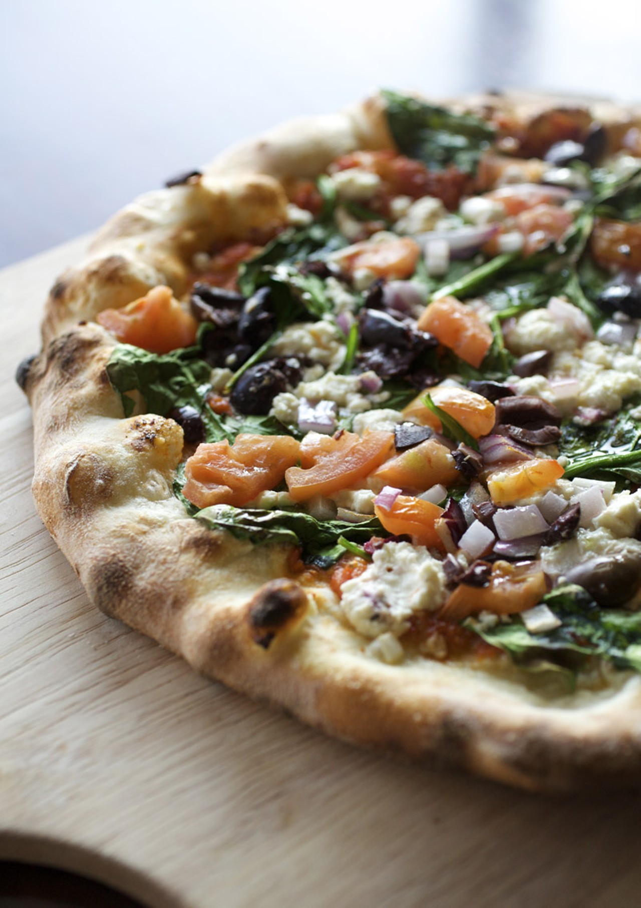 The Grecian Pizza is prepared in the wood burning oven with feta, baby spinach, roma tomatoes, kalamata olives, red onions and a sun-dried tomato pesto.