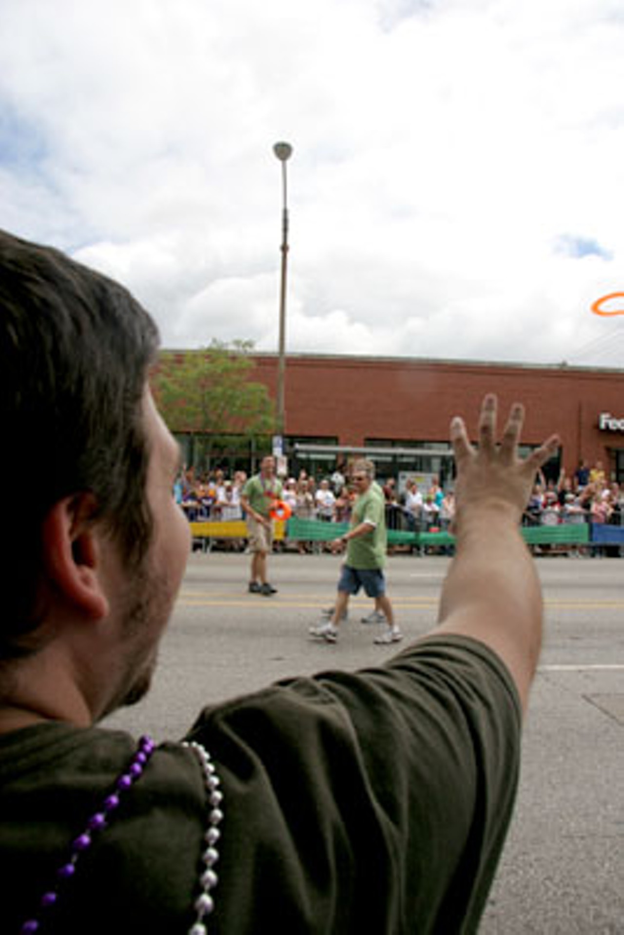 A parade spectator tries to catch a frisbee being thrown into the crowd.