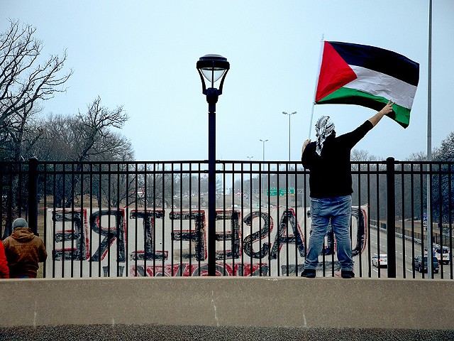 Mohammed Ghannam, right, waves a Palestinian flag to drivers on I-44 from Tamm Avenue during a protest for Palestinian liberation on Friday, Feb. 2, 2024.