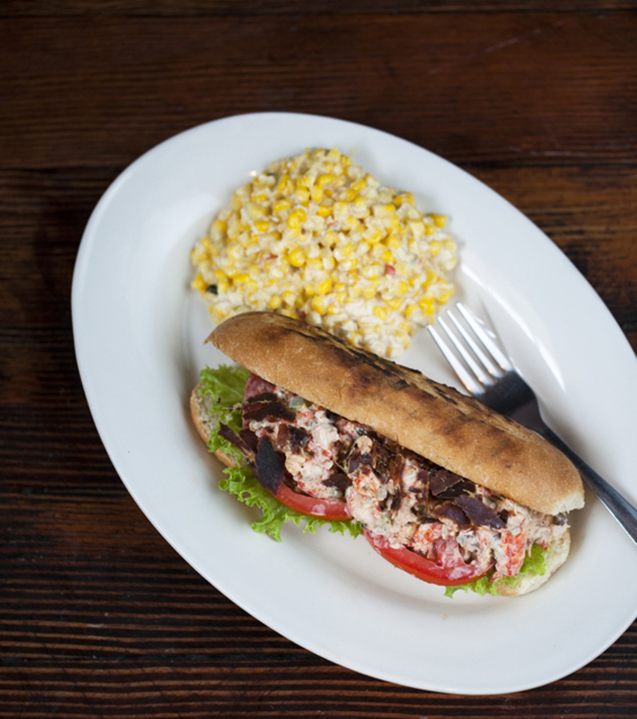 The Crawfish Salad sandwich, prepared with oven dried pancetta, tomatoes, and basil. Shown with a side of cream corn.