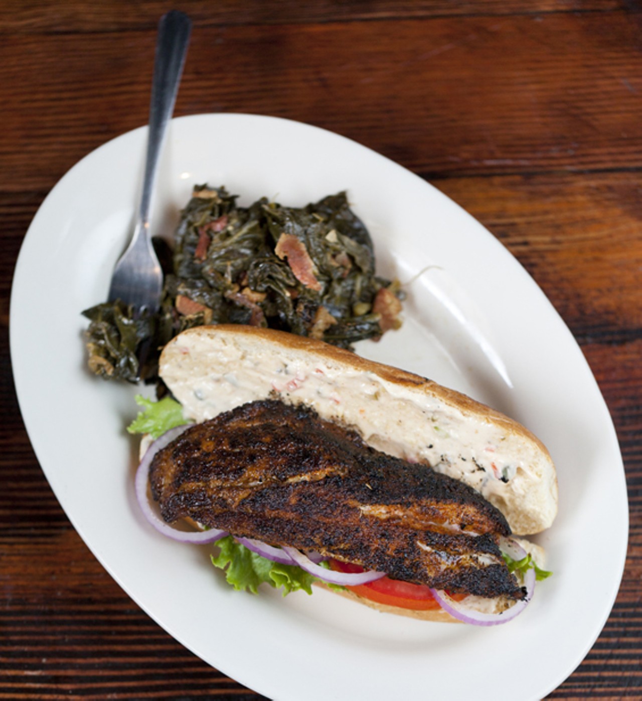 The Grouper Sandwich can be served grilled, fried or blackened - with lettuce, tomato, onion, and remoulade. Shown here blackened with a side of collard greens made with bacon, onion, and garlic.