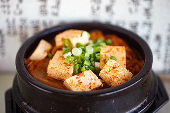 Kimchi jjigae, or fermented kimchi soup with pork and tofu, topped with scallions.