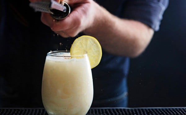 A bartender grates something onto a cocktail.