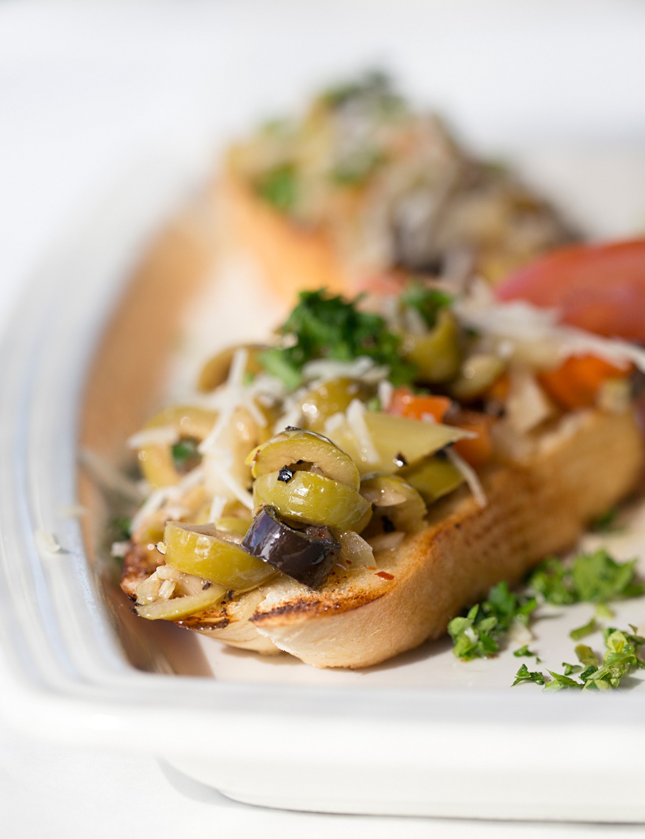 Muffaletta olive bruschetta is a house recipe served on toasted French bread.