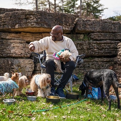 Grayland Holmes feeds his dogs in Forest Park. Every Wednesday, Holmes loads his dogs into his car, picks up a bucket of KFC and celebrates what he calls “woof woof Wednesdays” at Forest Park.
