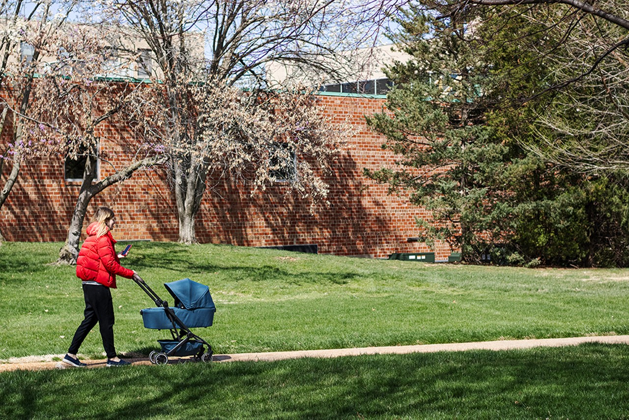 A woman walks a baby in a stroller along the campus of Saint Louis University.