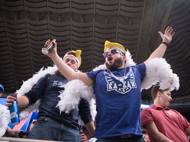 Two people wearing eagle hats stand in The Dome at America’s Center. The person in the front spreads his arms out while wearing a "Ka-Kaw" shirt.