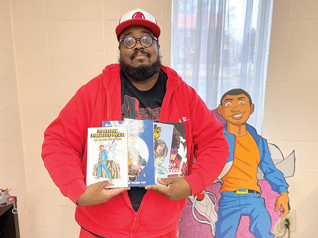 David Gorden poses with a selection of comics he's released to date.